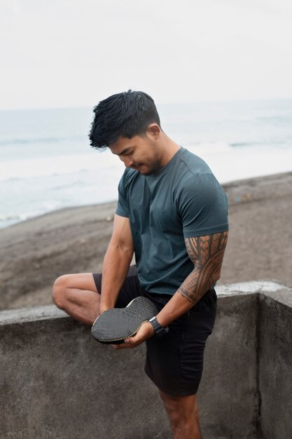 Vue latérale homme qui s'étend à la plage