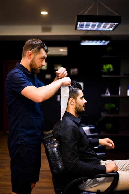 Vue latérale d'un homme qui se coupe les cheveux