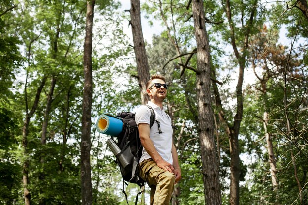 Vue latérale homme avec sac à dos en forêt