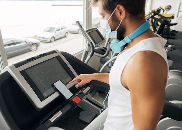 Vue latérale de l'homme à la salle de sport à l'aide d'un tapis roulant