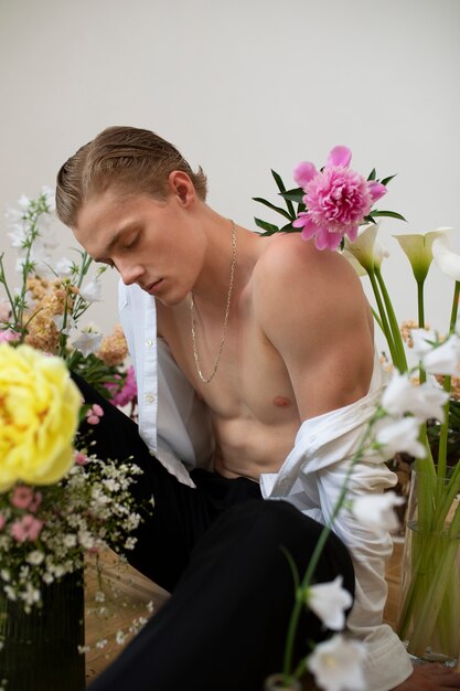 Vue latérale homme sensible posant avec des fleurs