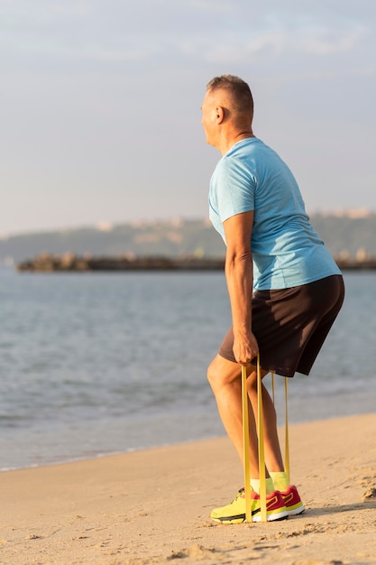 Vue latérale de l'homme travaillant avec une corde élastique sur la plage