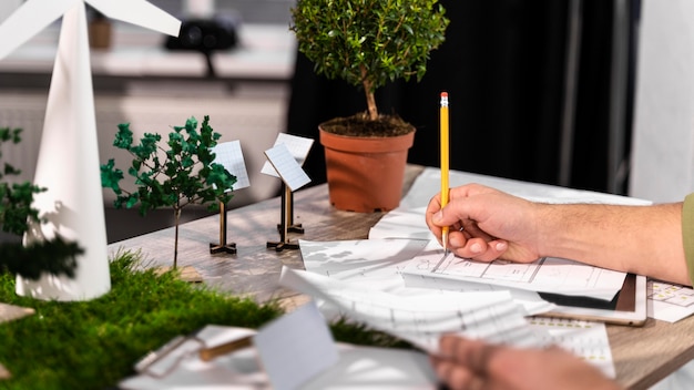 Vue latérale de l'homme travaillant sur un projet d'énergie éolienne écologique avec des plans papier