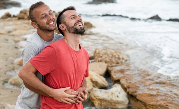 Vue latérale des hommes heureux au bord de la mer