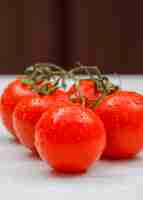 Photo gratuite vue latérale humide de tomates fraîches sur une surface blanche