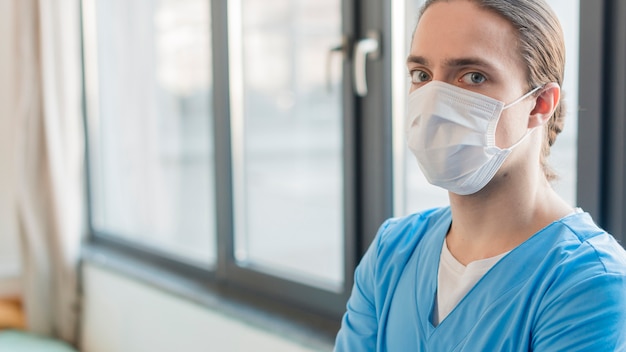 Vue latérale infirmière mâle avec masque médical