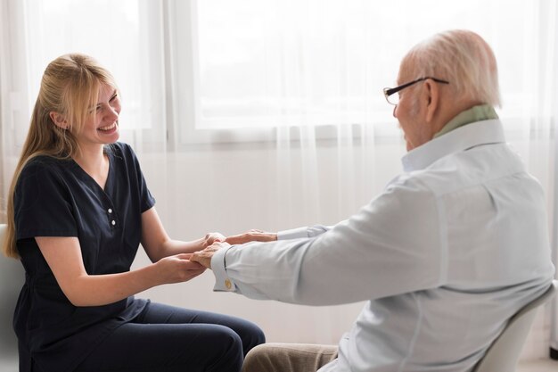 Vue latérale de l'infirmière tenant les mains de l'homme senior