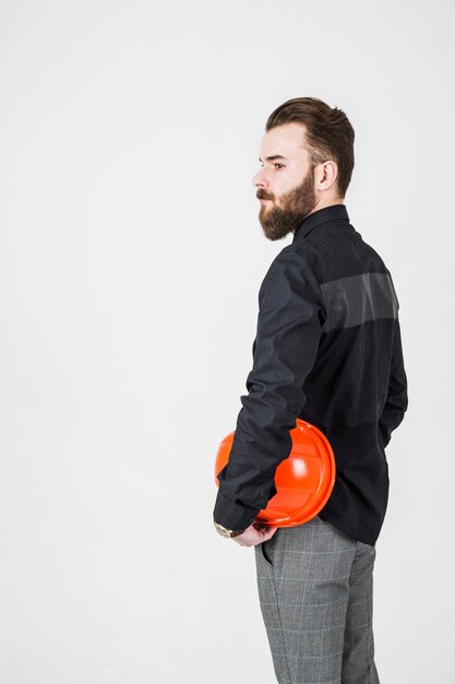 Vue latérale de l&#39;ingénieur masculin tenant le casque debout sur fond blanc