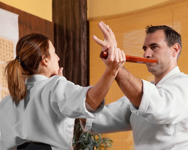 Vue latérale d'un instructeur d'arts martiaux masculin dans la salle de pratique avec une stagiaire