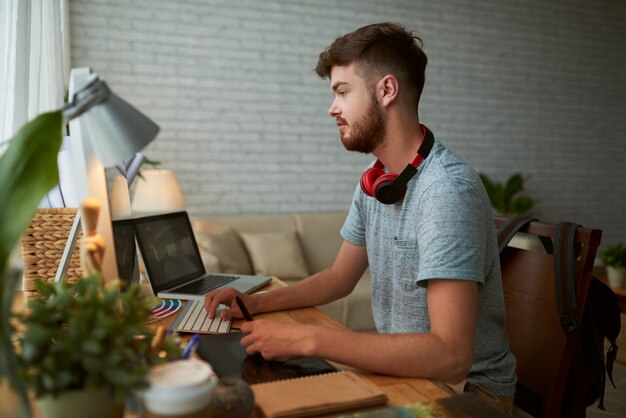 Vue latérale d'un jeune étudiant à faire ses devoirs de classe de design