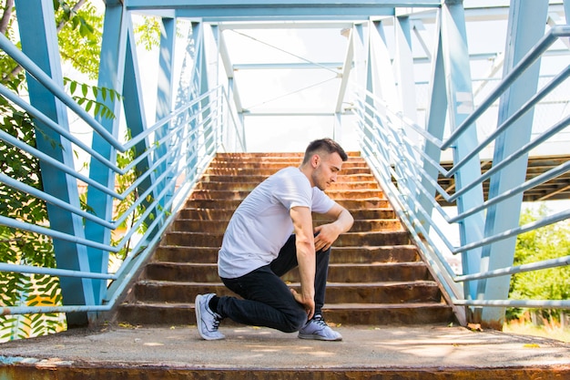 Vue latérale d&#39;un jeune homme beau, posant sur l&#39;escalier