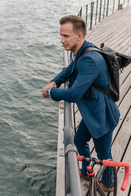 Photo gratuite vue latérale jeune homme debout à côté de son vélo