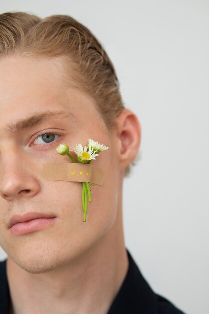 Vue latérale jeune homme avec une fleur sur la joue