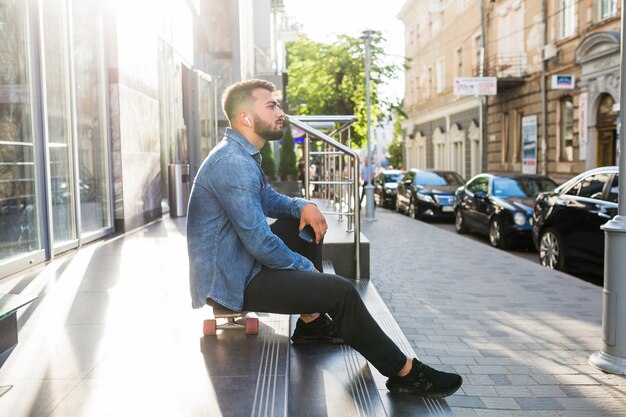 Vue latérale d&#39;un jeune homme reposant sur une planche à roulettes