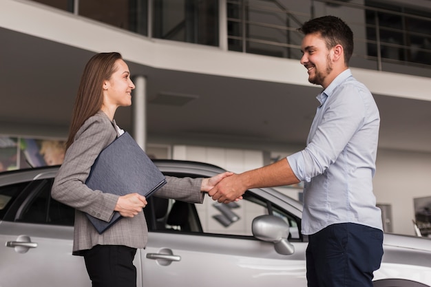 Vue latérale jeune homme se serrant la main avec le concessionnaire automobile