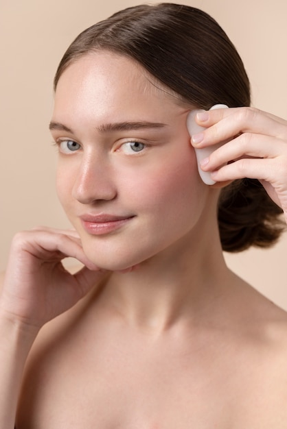 Photo gratuite vue latérale jeune mannequin utilisant gua sha