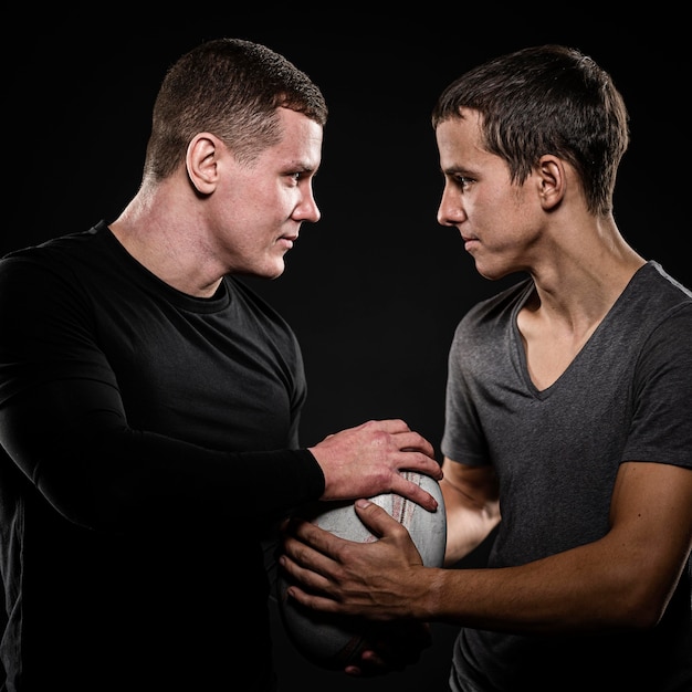 Photo gratuite vue latérale des joueurs de rugby masculins tenant le ballon avec les mains