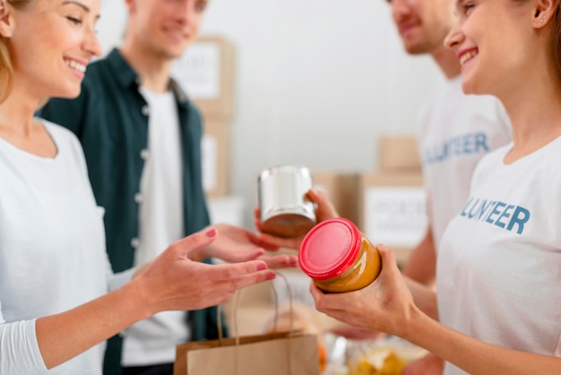 Vue latérale de joyeux bénévoles donnant des dons alimentaires