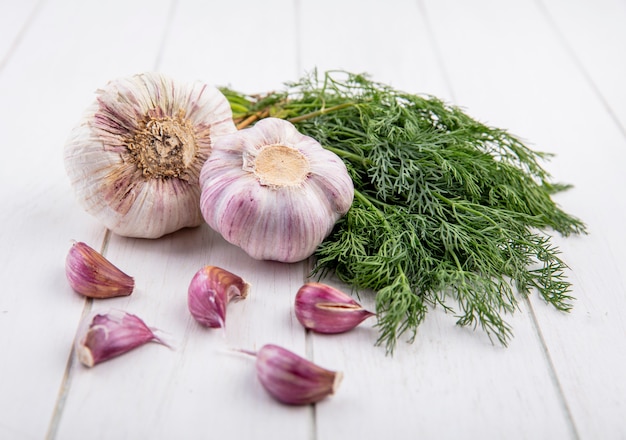 Photo gratuite vue latérale des légumes comme bouquet d'aneth et bulbe d'ail avec des gousses d'ail sur bois