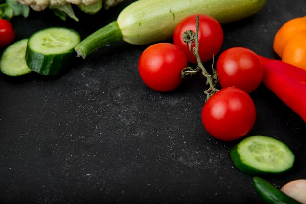 Vue latérale des légumes comme des courgettes de concombre tomate sur fond noir avec copie espace