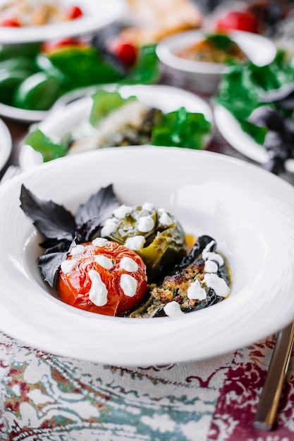 Vue latérale de légumes farcis à la viande et à la crème dans une assiette blanche