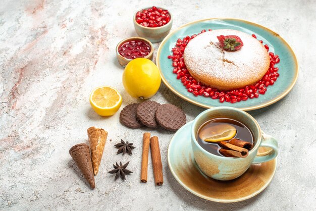 Vue latérale de loin gâteau aux fraises une tasse de thé le gâteau à côté des baies de citron