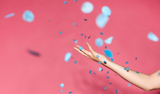 Vue latérale main de femme avec des confettis bleus