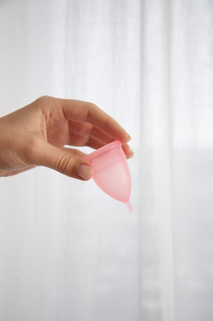 Vue latérale main tenant une coupe menstruelle