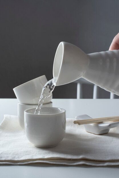 Vue latérale main versant une boisson au saké