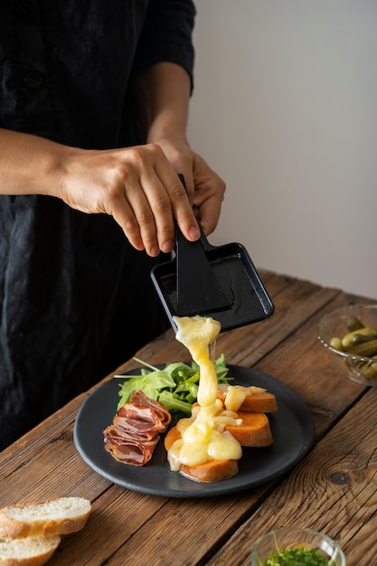 Vue latérale des mains mettant du fromage sur la nourriture