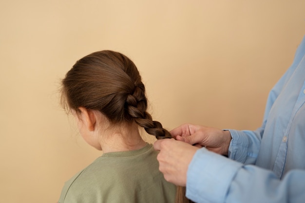 Photo gratuite vue latérale mains tressant les cheveux de la fille