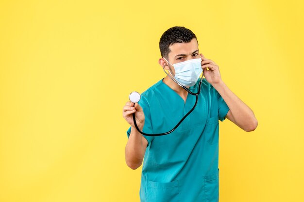 Vue latérale d'un médecin un médecin en masque avec phonendoscope parle avec les patients