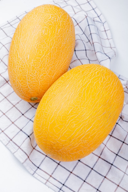 Vue latérale des melons sur tissu à carreaux et fond blanc