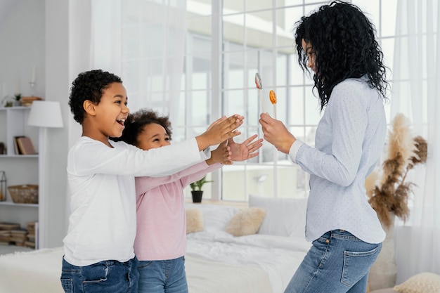 Photo gratuite vue latérale de la mère donnant à ses enfants des sucettes