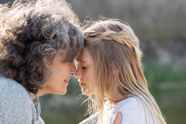 Vue latérale d'une mère pressant son front contre celui de sa fille