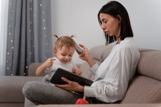 Vue latérale mère avec tablette et bébé