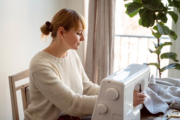 Vue latérale sur mesure femme à l'aide de machine à coudre