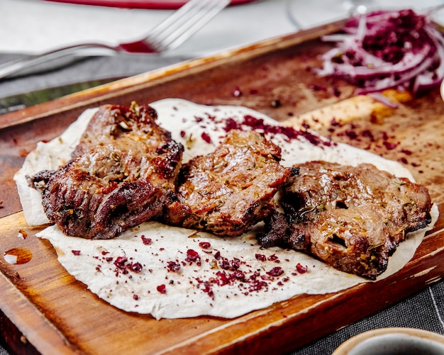 Vue latérale des morceaux de viande rôtie sur une planche de bois