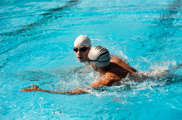 Vue latérale des nageurs masculins nageant dans la piscine