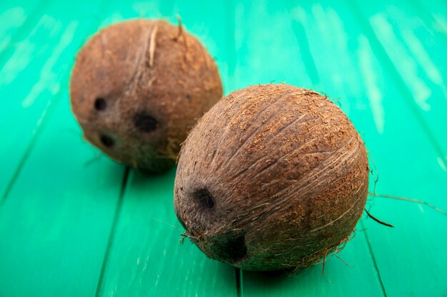 Vue latérale des noix de coco brunes et fraîches sur la surface verte