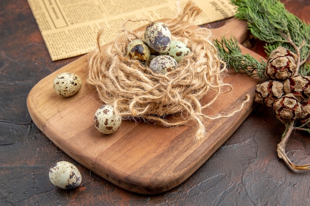 Vue latérale d'œufs frais de ferme avicole biologique dans un bol en bois sur une planche à découper et un vieux journal sur fond marron