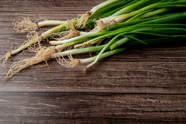 Vue latérale des oignons verts sur fond en bois avec espace copie