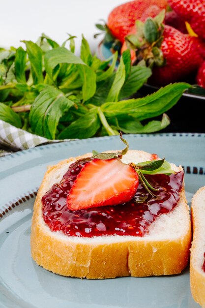 Vue latérale pain grillé aux fraises pain blanc avec confiture de fraises et menthe sur la table