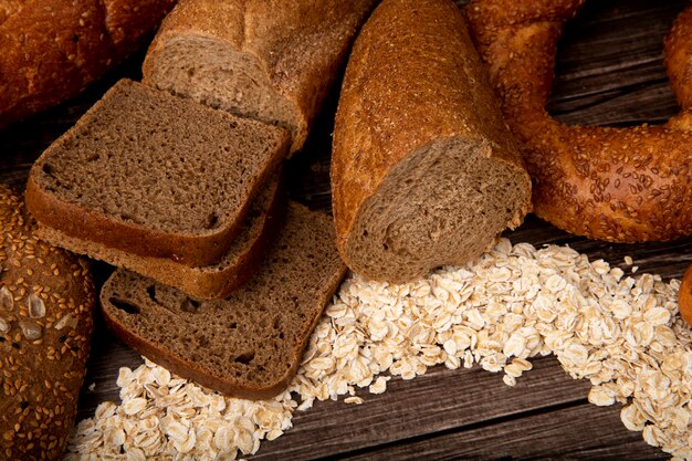 Vue latérale des pains en tranches de pain de seigle coupé en demi bagel baguette avec des flocons d'avoine sur fond de bois