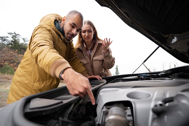 Vue latérale des personnes vérifiant la voiture