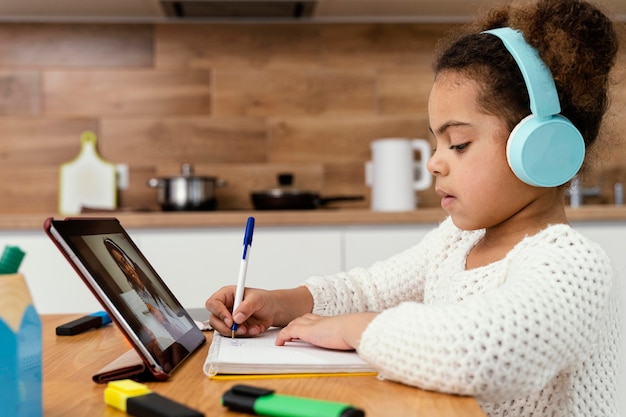 Vue latérale de la petite fille au cours de l'école en ligne avec tablette