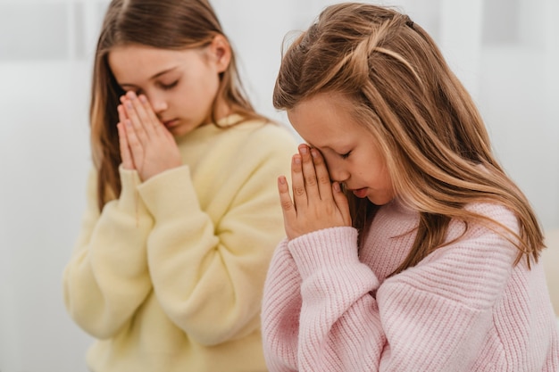 Photo gratuite vue latérale des petites filles priant à la maison