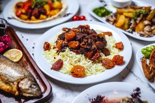 Vue latérale pilaf aigre avec ragoût d'agneau châtaignes et fruits secs sur une plaque