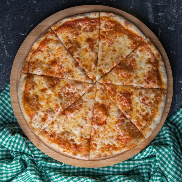 Vue latérale pizza fermée avec chiffon à carreaux en planche ronde