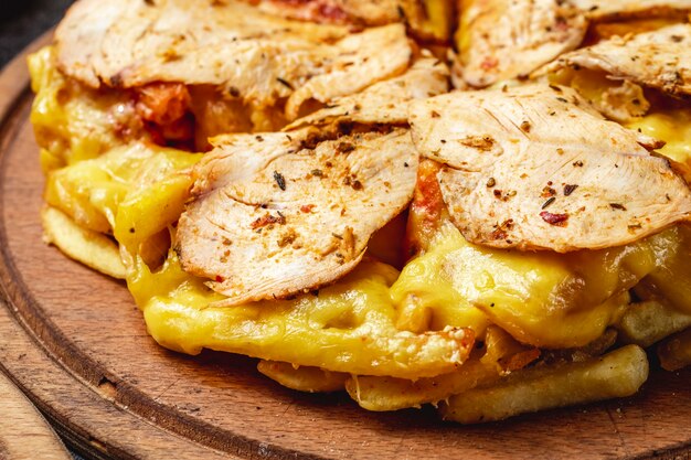 Vue latérale pizza frites avec du poulet fondu et du fromage fondu sur une planche